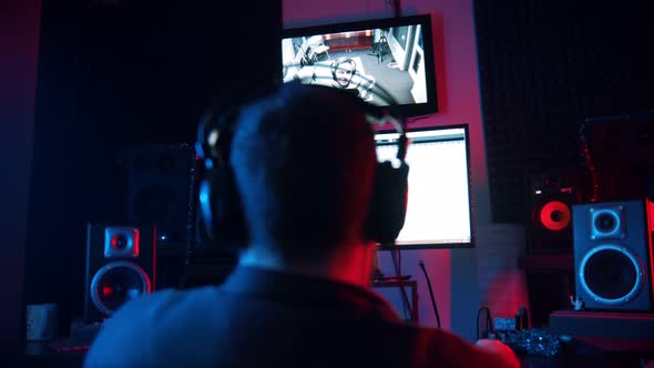 A Man Sound Engineer in Headphones Working in the Neon Sound Recording Studio - Recording a Rap