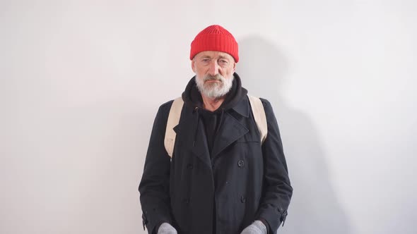 Poor Old-aged Bum in Red Hat and Street Wear Holding Cardboard Sign