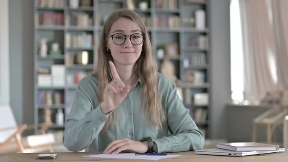 Young Woman Saying No with Finger Sign While Sitting in Office