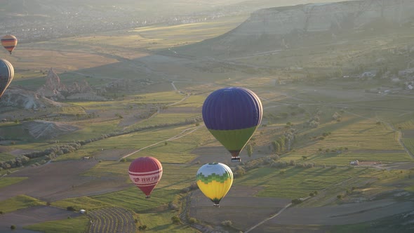 Hot air balloons fly over the mountainous landscape of Cappadocia, Turkey.