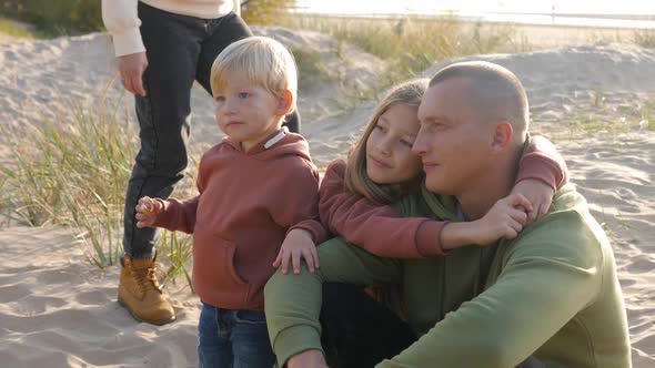 Family with a Son and Daughter and a Dog Sit on the Sand