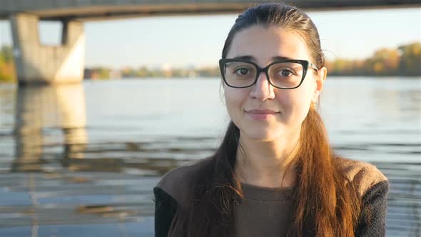 Beautiful Girl in Glasses is Looking Into the Camera and Smiling