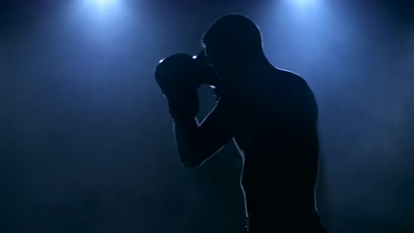 Young Male Athlete Boxing in the Studio Visible in Silhouette