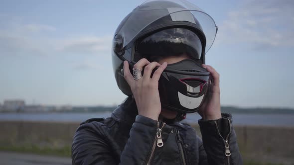 The Young Woman Taking Off the Motorcycle Helmet and Looking Into the Camera Smiling Close-up. Hobby