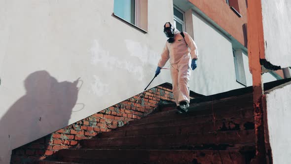 Sanitation Worker Is Disinfecting the Stairs While Walking Along It