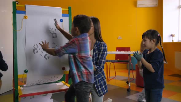 Cheerful Diverse Kids Painting Handprints at Class