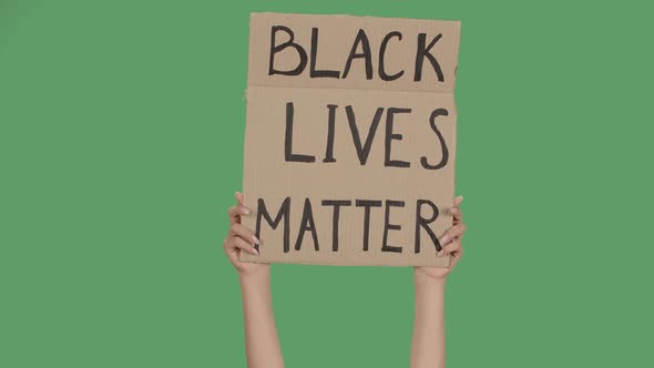 Sign BLACK LIVES MATTER Against the Background of a Green Screen, Chroma Key. Hands Hold Poster From