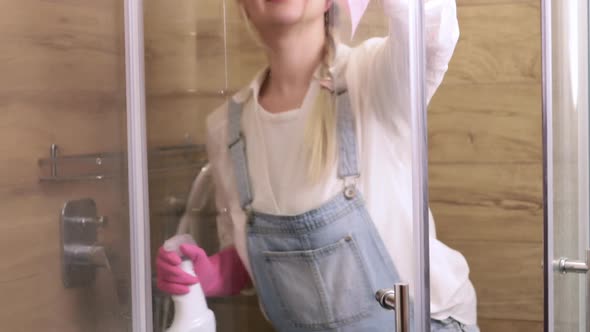 A Beautiful Housewife Cleans the Glass of the Shower Cabin From Plaque