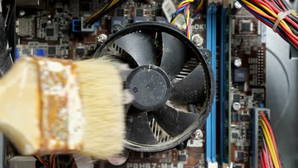 Master of the Service Center Cleans the Fan of the System Unit with a Brush Closeup
