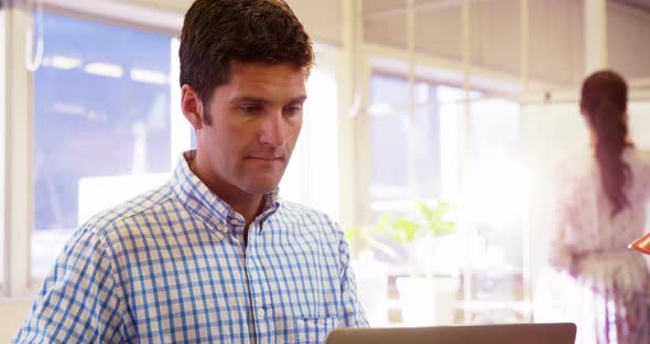 Male business executive having coffee while using laptop