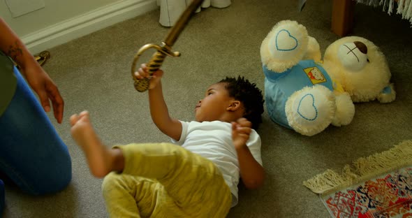 High angle view of cute little black boy playing and lying on floor of comfortable home 4k