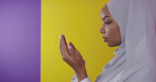 Modern African Muslim Woman Makes Traditional Prayer to God Over Colorfull Background