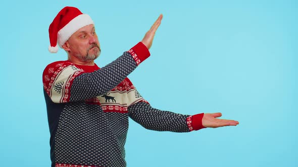 Man Wears Red Christmas Deer Sweater Showing Thumbs Up and Pointing at on Blank Advertisement Space