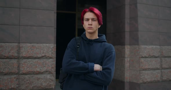 Portrait of Millennial Young Man Wearing Dark Hoodie Crossing Arms and Looking To Camera. Crop View