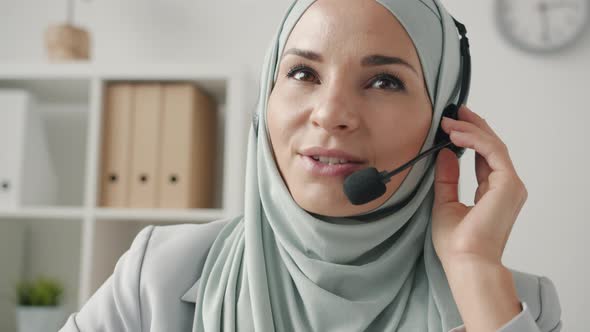 Portrait of Hijabi Lady Chatting with Microphone and Headphones Talking to Customer in Call Center