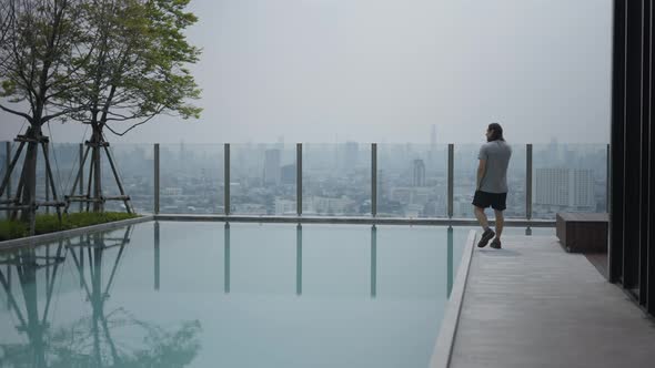 Casual Man Is Talking On His Smartphone Near The Pool On Hotel Rooftop