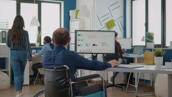 Young Worker with Disabilities Analyzing Statistics Datas Sitting in Wheelchair