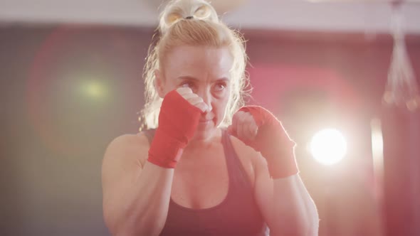 Close up of caucasian female boxer practicing her punches at the gym