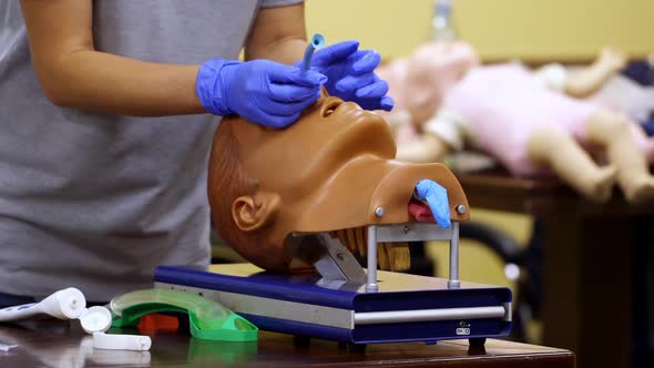 Medic shows how to insert oxygen tube in nose of a medical dummy. 