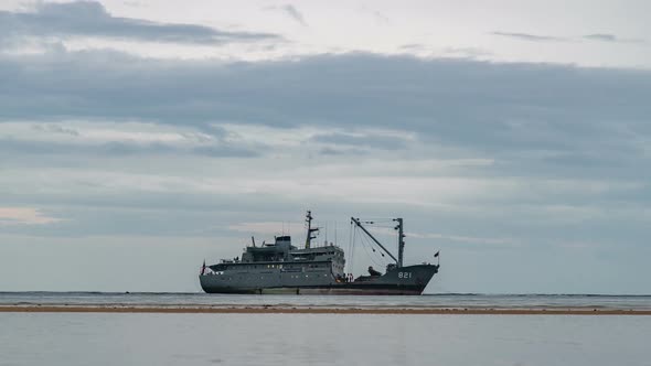 The ship stands in the sea aground in cloudy weather, transition day to night