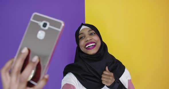 Portrait of Smiling African Black Muslim Girl Posing at Color Studio Background Taking Selfie Photo