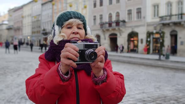 Senior Old Woman Tourist Taking Pictures with Photo Camera Using Retro Device in Winter City Center