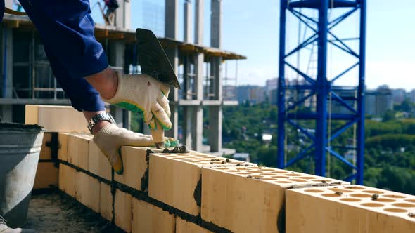 A Brick Is Getting Inserted and Leveled in the Building Wall