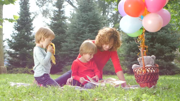 Happy Mother with Child Daughter in Park Reading Book