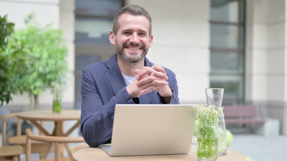 Man Smiling at Camera While Using Laptop Outdoor