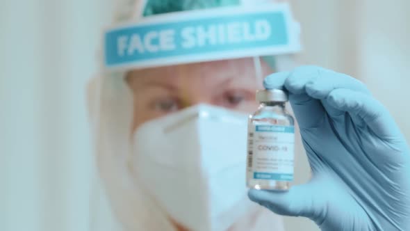 Doctor in a Protective Form Holds an Ampoule with the Vaccine Against CORONAVIRUS.