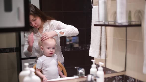 mother combing her little daughter in the morning in the bathroom