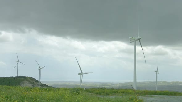 Wind Turbines Spinning in Green Field Under Gray Stormy Sky, Bad Rainy Weather