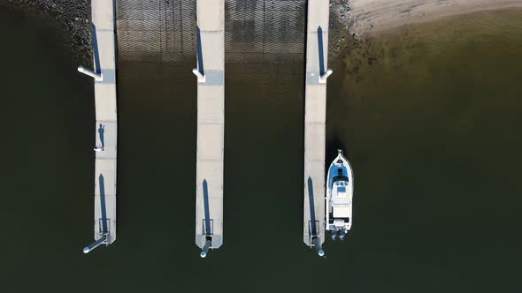 Unique view of a single boat docked at a public boat ramp facility next to a fisherman. High drone v