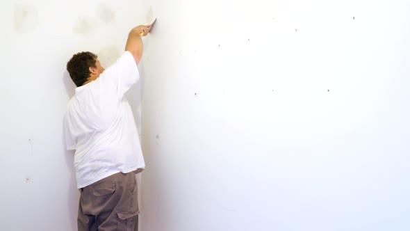 Hand with a Spatula Plaster on a Wall