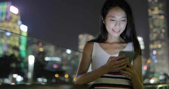 Woman using mobile phone in Hong Kong city at night 