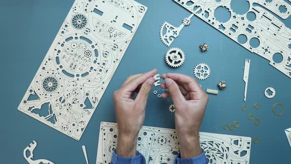 Man assembling flywheels and small pieces of wooden puzzle toy.