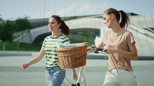 Video of two women walking and talking with a white bike. Shot with RED helium camera in 8K. 