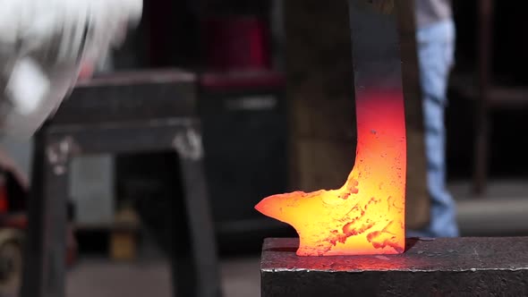 Blacksmiths forging hot metal with hammer in workshop