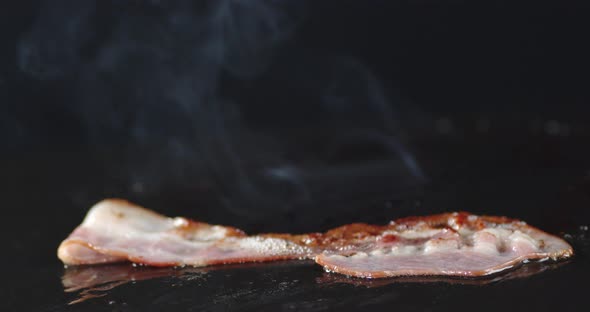 A Piece of Bacon in a Frying Pan with Hot Steam. 