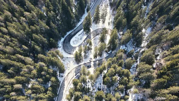 Aerial drone view of the spring Carpathians, Romania. Valley with road and moving cars, forest partl