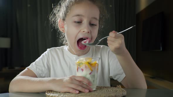 Child Eats Milk Yogurt with Tropical Fruits