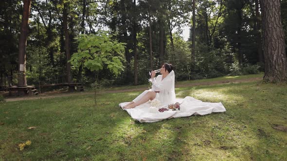 Wedding Bride in Boudoir Dress Sitting in Morning Garden Drinking Champagne Woman in Night Gown Veil