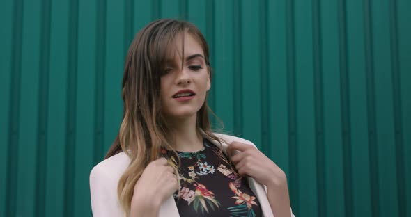 Portrait of Satisfied Girl in Suit Posing Near Fence at Camera