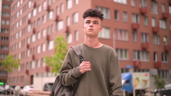 Young stylish guy walks through the city thinking