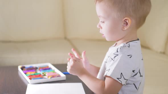 Kid Boy Playing with Plasticine at Home. Creative Kid with Play Clay Molding at the Table.