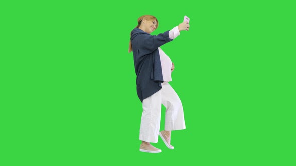 Happy Young Pregnant Woman Taking Selfie on a Green Screen, Chroma Key.
