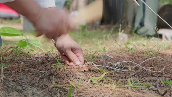 Female hands use rubber hammers hit anchor for camping or to strengthen the tent from the wind.