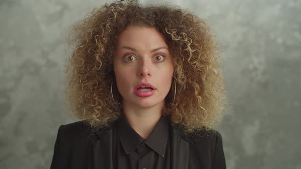 Shocked Pretty Woman with Curly Hair Looking with Astonished Expression