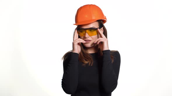 Joyful Woman in Orange Helmet for Building is Trying on Goggles and Posing 