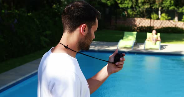 Lifeguard looking at stopwatch near the poolside